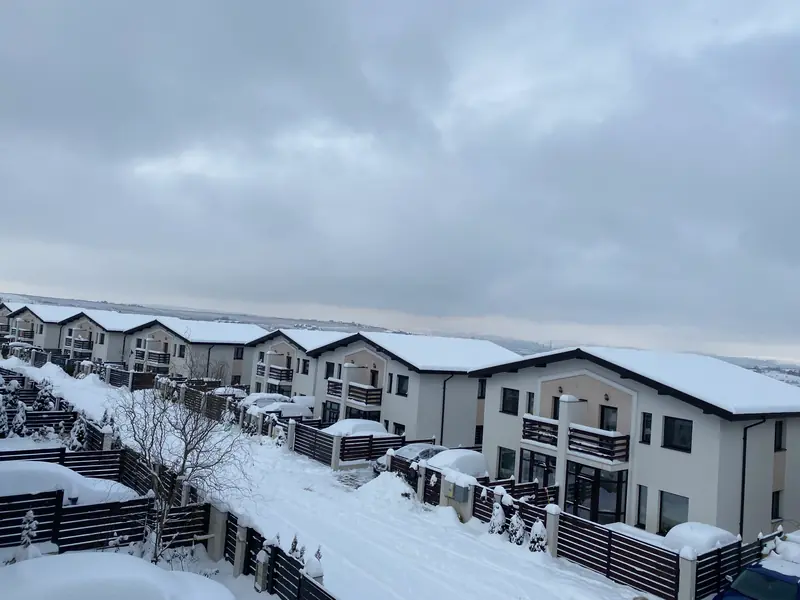 Strada din La Brazi Residence iarna: drum betonat și case duplex
