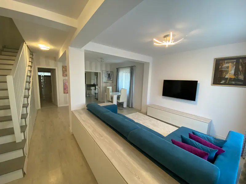 Livingul de la parter, deschis spre zona de masă, cu scara spre etaj