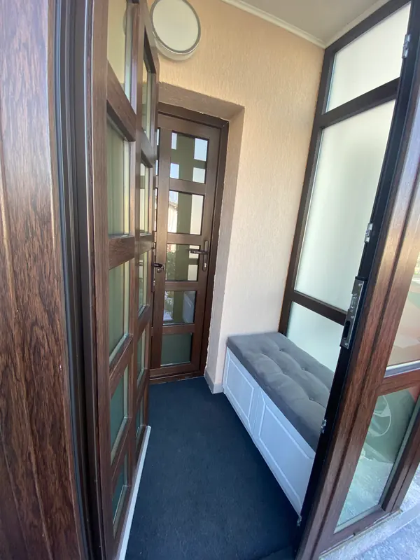 Veranda de la intrare, închisă cu tâmplărie, cu bancă de depozitare